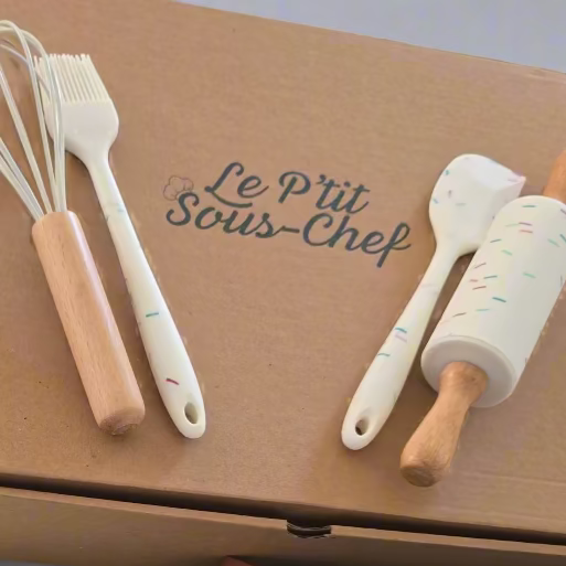 Box with kitchen tools and apron on a concrete surface, featuring 'Le Pit Sois Chef' branding.